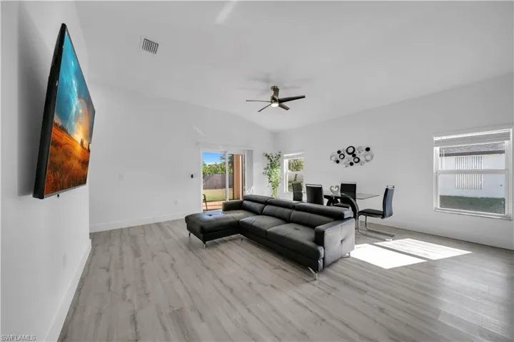 Living area with light wood-type flooring, healthy amount of natural light, a desk, a ceiling fan, and lofted ceiling