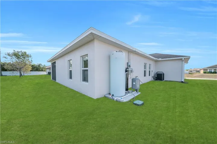 Back of property with a yard and stucco siding