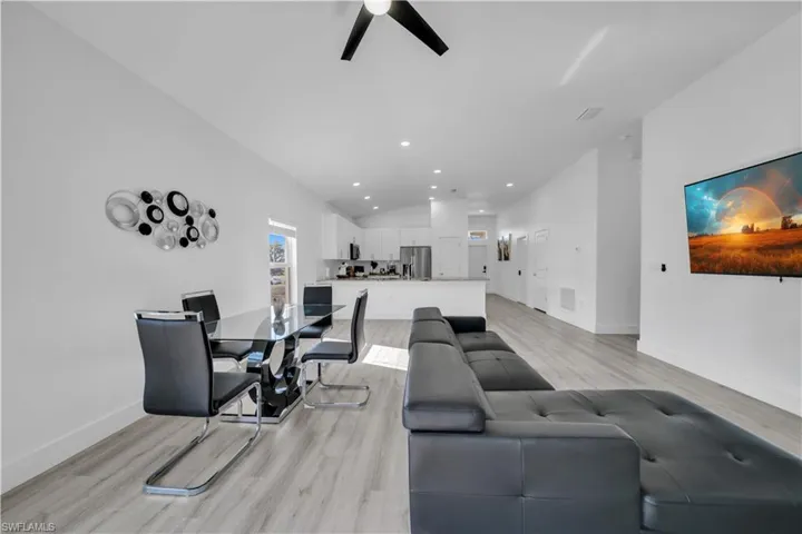 Living room with light wood-style floors, recessed lighting, a ceiling fan, and lofted ceiling