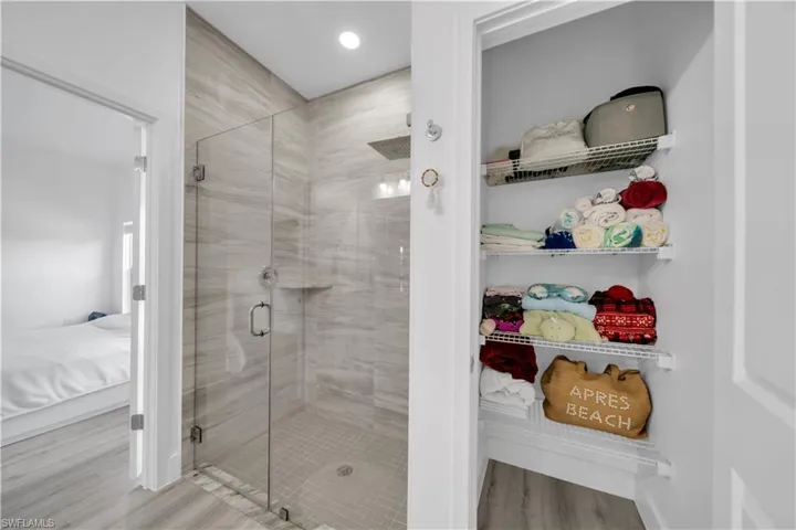 Ensuite bathroom with light wood-type flooring, a shower stall, and a closet