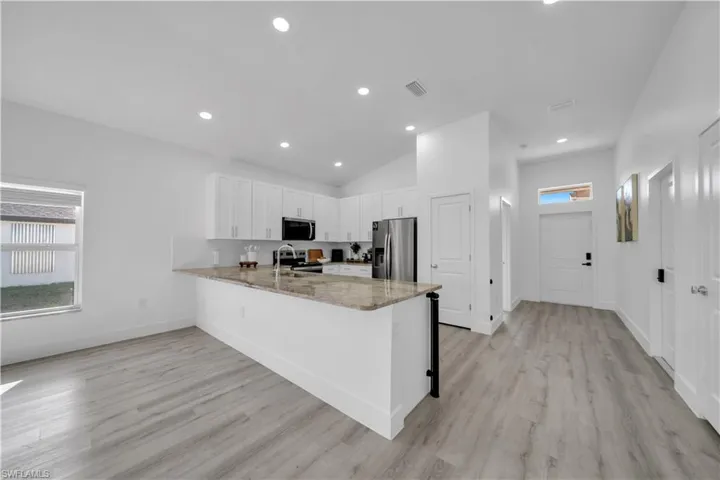Kitchen featuring plenty of natural light, light stone countertops, stainless steel appliances, a peninsula, and recessed lighting