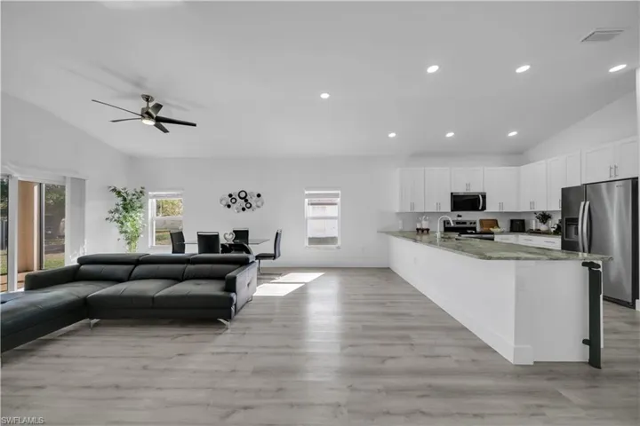 Living room with vaulted ceiling, light wood-type flooring, ceiling fan, and recessed lighting