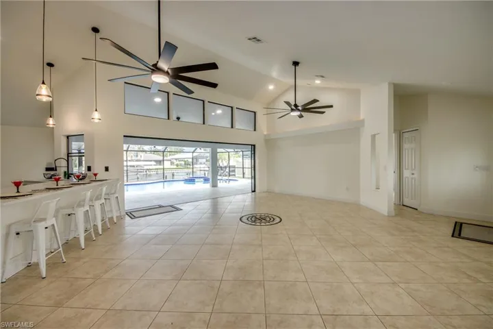 Tiled empty room featuring high vaulted ceiling and ceiling fan