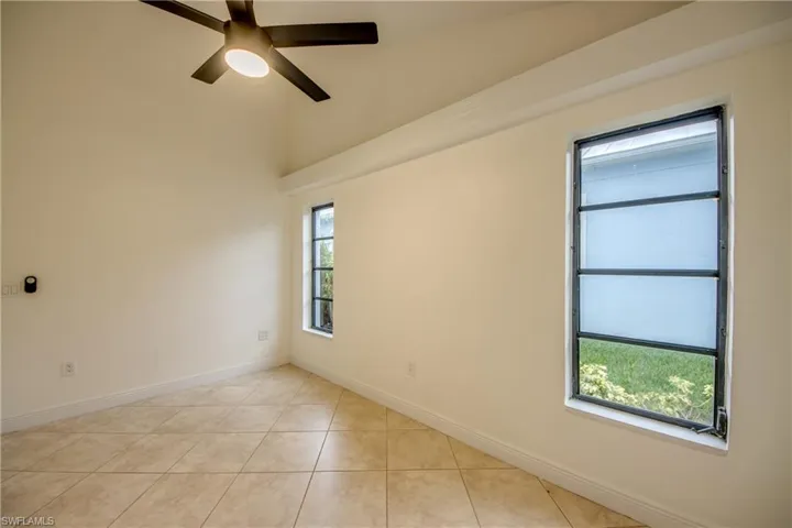 Tiled empty room featuring a healthy amount of sunlight and ceiling fan