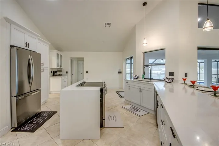 Kitchen featuring stainless steel fridge, light tile flooring, and pendant lighting