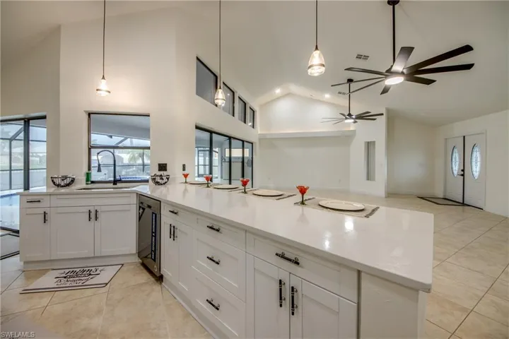 Kitchen with ceiling fan, kitchen peninsula, light tile flooring, pendant lighting, and white cabinets