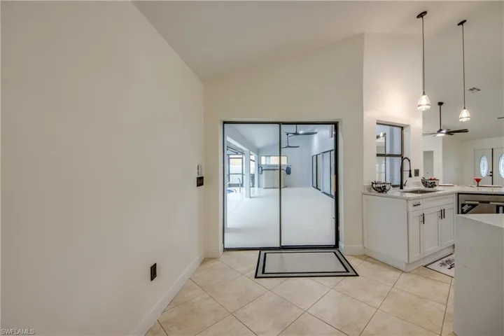 Kitchen with plenty of natural light, ceiling fan, white cabinets, and light tile floors