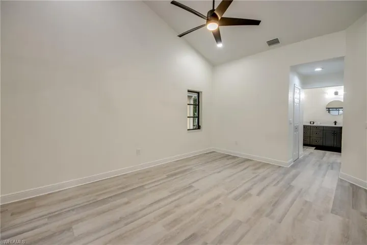 Empty room featuring high vaulted ceiling, ceiling fan, and light hardwood / wood-style floors
