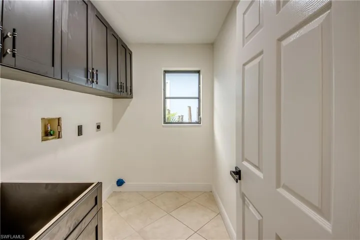 Laundry room featuring electric dryer hookup, cabinets, washer hookup, and light tile floors