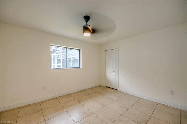 Empty room with ceiling fan and light tile floors