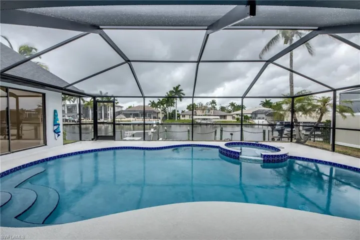View of swimming pool with glass enclosure and an in ground hot tub