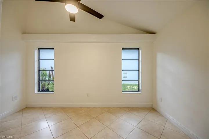 Tiled empty room featuring lofted ceiling and ceiling fan