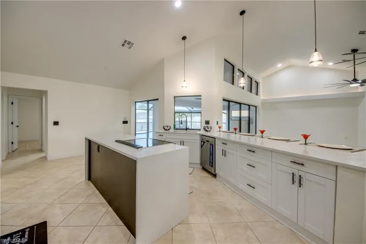 Kitchen with beverage cooler, decorative light fixtures, white cabinets, and a kitchen island