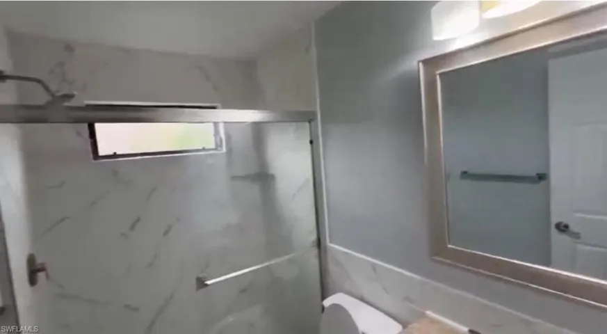 Bathroom with vanity and a marble finish shower