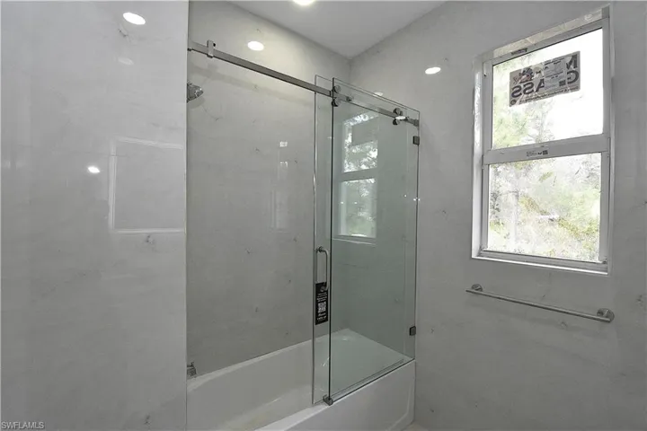 bathroom featuring walls completely tiled and glass sliding door.