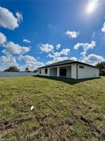View of side of property featuring a yard, fence, and stucco siding