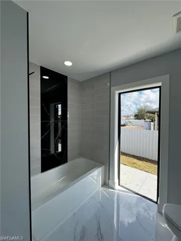 Bathroom with recessed lighting, a bathing tub, toilet, visible vents, and marble finish floor