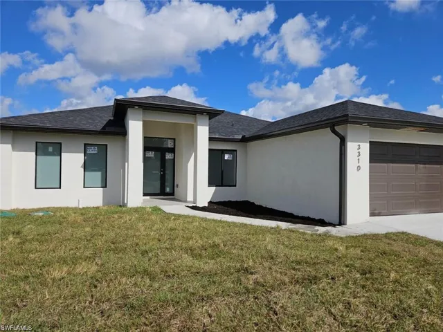 View of front of home with an attached garage, driveway, stucco siding, and a front lawn