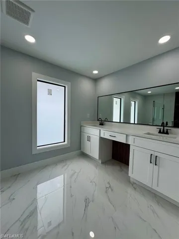 Bathroom featuring baseboards, double vanity, a sink, and visible vents