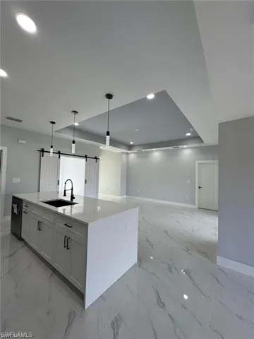 Kitchen featuring marble finish floor, a barn door, baseboards, and a sink