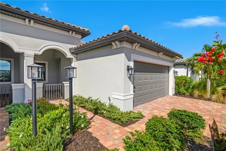 View of side of property with stucco siding, a garage, driveway, and a tile roof