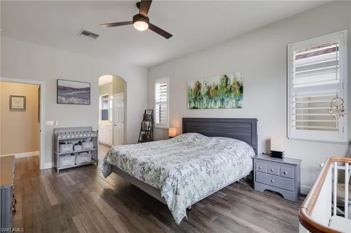 Bedroom featuring ceiling fan, ensuite bath, and hardwood / wood-style flooring
