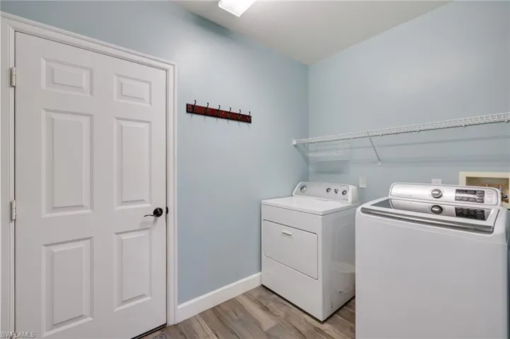 Laundry area with wood-style floors, hookup for a washing machine, and washing machine and clothes dryer