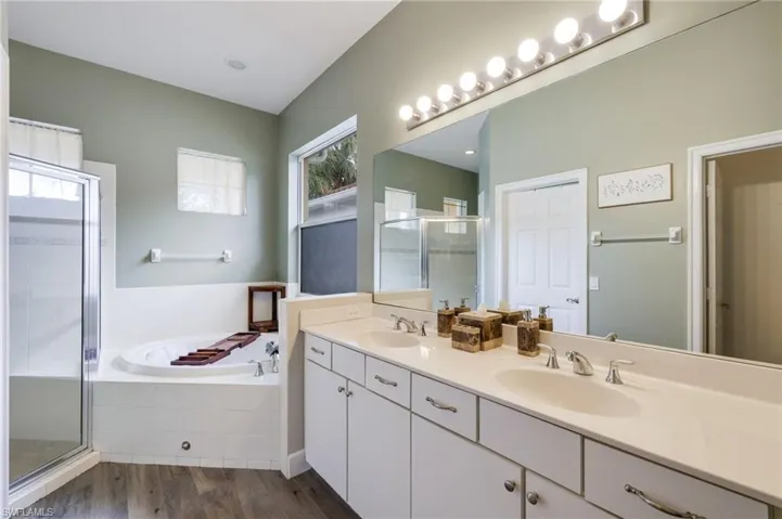 Bathroom with dual bowl vanity, hardwood / wood-style flooring, and separate shower and tub