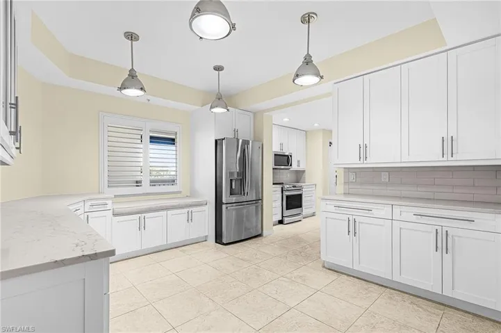 Kitchen featuring white shaker-style cabinetry, light-toned countertops, and stainless steel appliances