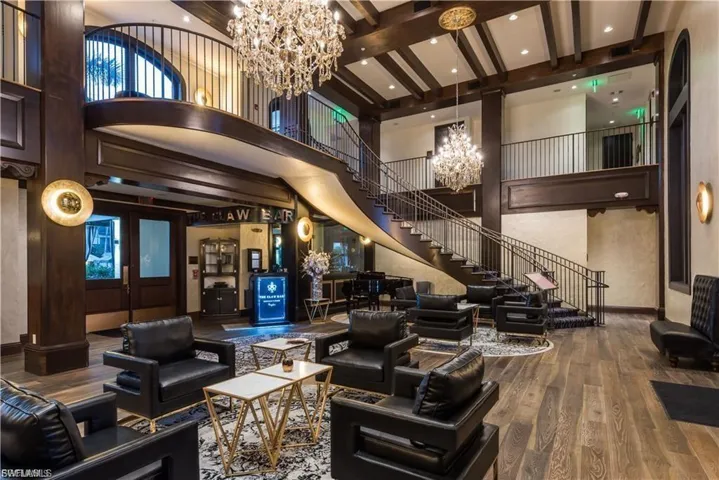 Grand foyer featuring a coffered ceiling with exposed wood beams, a curving staircase with wrought iron railing, and wood-finish flooring