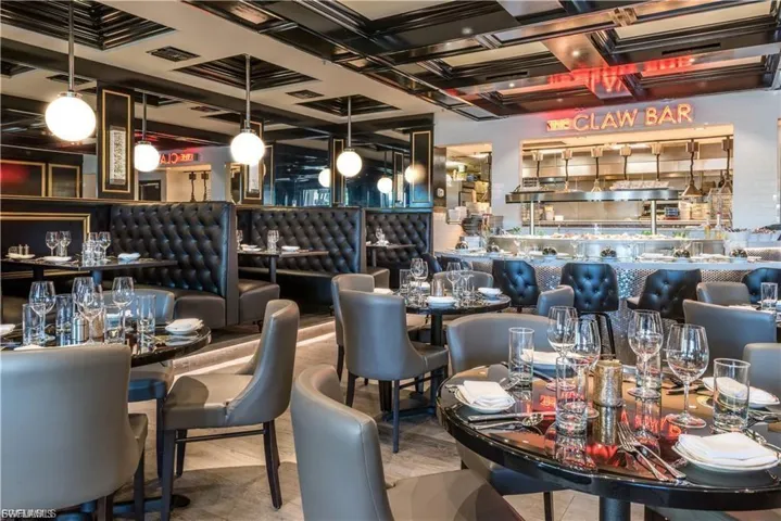 Refined dining area featuring booth seating with tufted upholstery, round tables with a glossy finish, and sleek pendant lighting