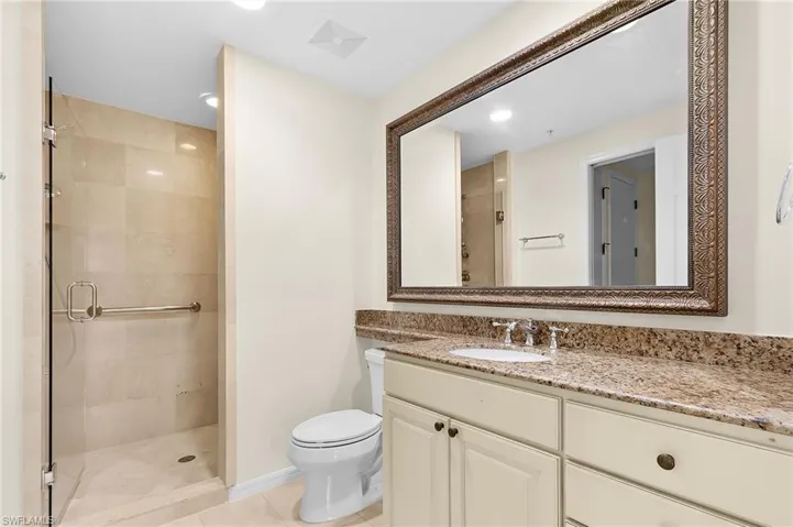 Bathroom featuring a walk-in shower with glass enclosure, beige tiled walls, and a grab bar