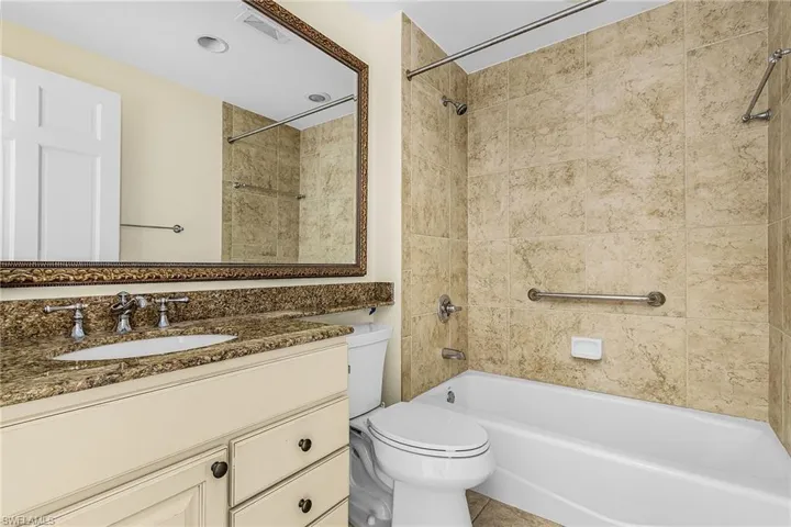 Bathroom with a single vanity featuring a stone countertop, an undermount sink, and a framed mirror