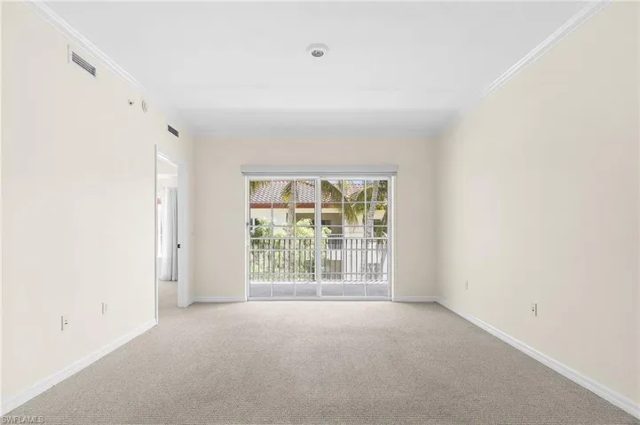 Living area featuring neutral wall tones, crown molding, light gray carpeting, and a sliding glass door leading to a private balcony