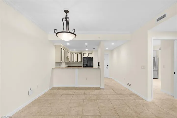 Open concept living space with light neutral walls, crown molding, and tiled flooring
