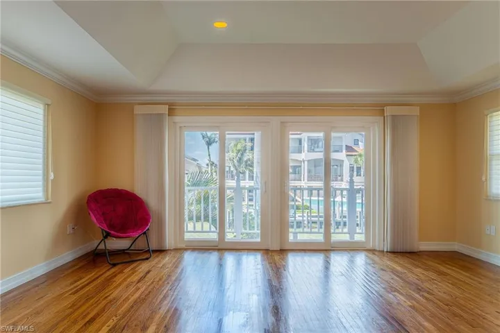 Empty room with a raised ceiling, wood finished floors, and baseboards