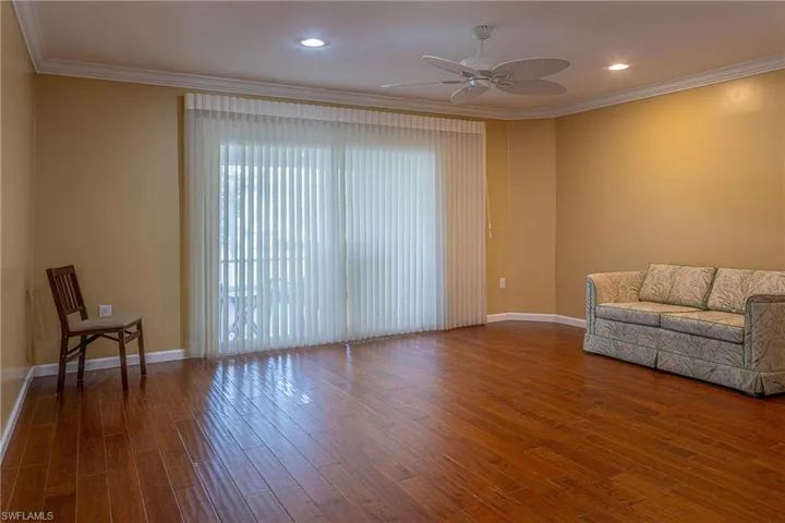 Living room featuring wood finished floors, crown molding, and ceiling fan