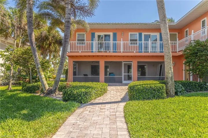 View of front of home with a front yard, a sunroom, a balcony, and stucco siding
