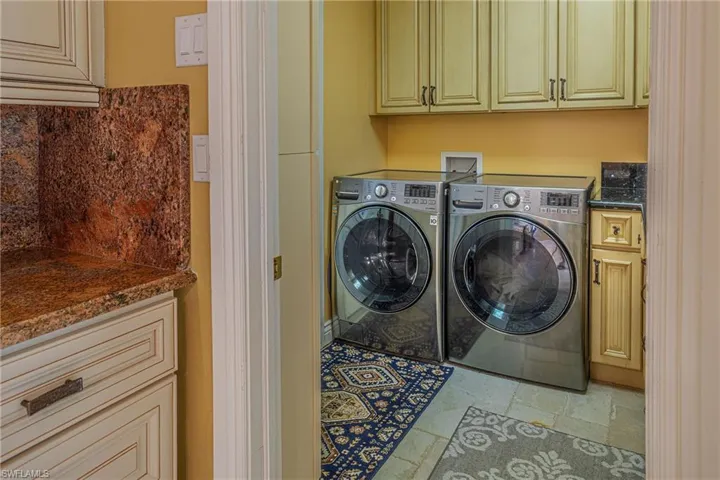 Washroom featuring stone tile flooring, separate washer and dryer, and cabinet space