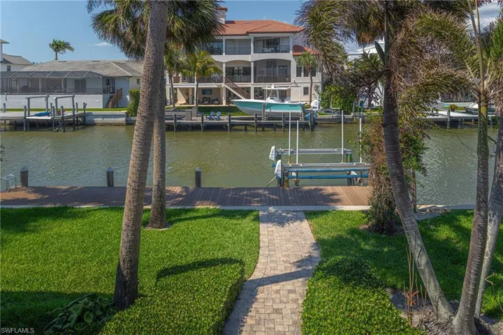 Dock area with a water view, a residential view, a yard, and boat lift