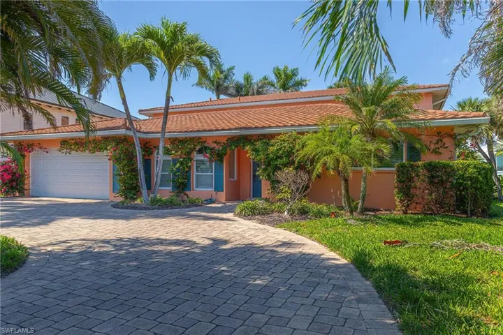 Ranch-style house with an attached garage, a tiled roof, stucco siding, and decorative driveway