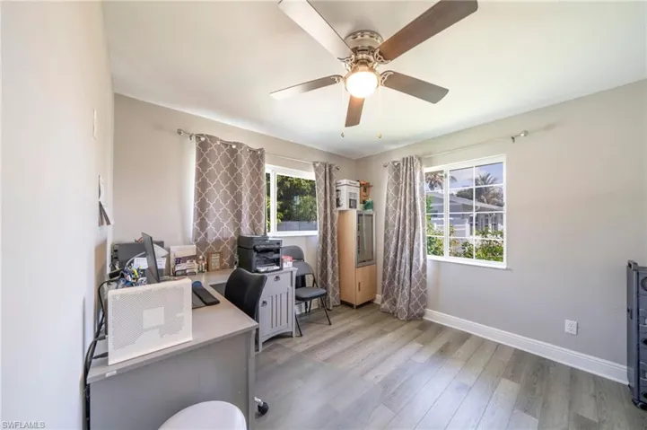 Office area with light wood-style floors and a ceiling fan