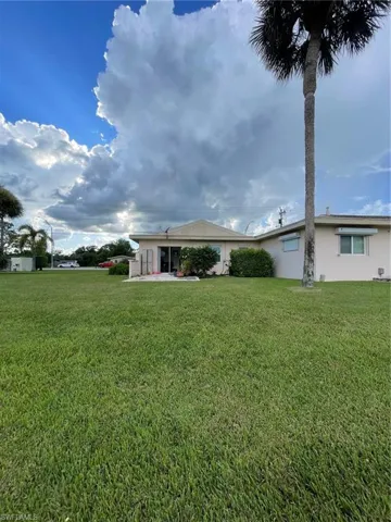 Back of property featuring stucco siding, a lawn, and a patio