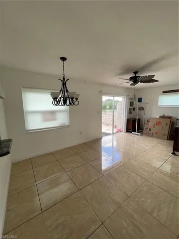 liing room with a ceiling fan, light tile patterned floors, and a chandelier