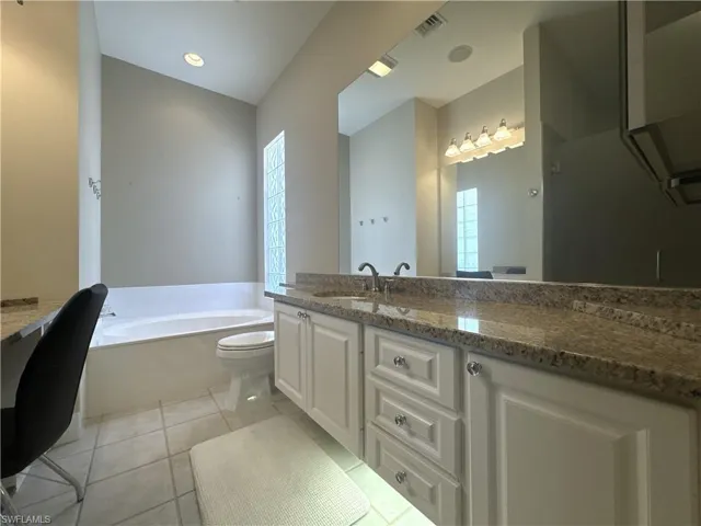 Spacious en-suite primary bath featuring dual vanities, a soaking tub, a unique walk-through shower with dual entrances, and two private water closets for added comfort and convenience