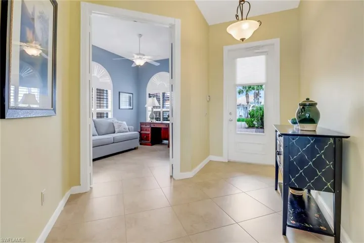 Entrance foyer featuring lofted ceiling, light tile patterned flooring, ceiling fan, and baseboards