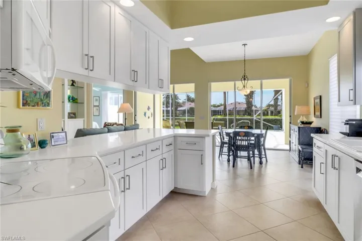 Kitchen featuring white microwave, white cabinetry, pendant lighting, and light tile patterned flooring