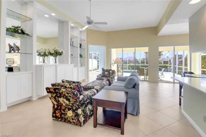 Living room featuring built in shelves, light tile patterned flooring, a ceiling fan, and recessed lighting