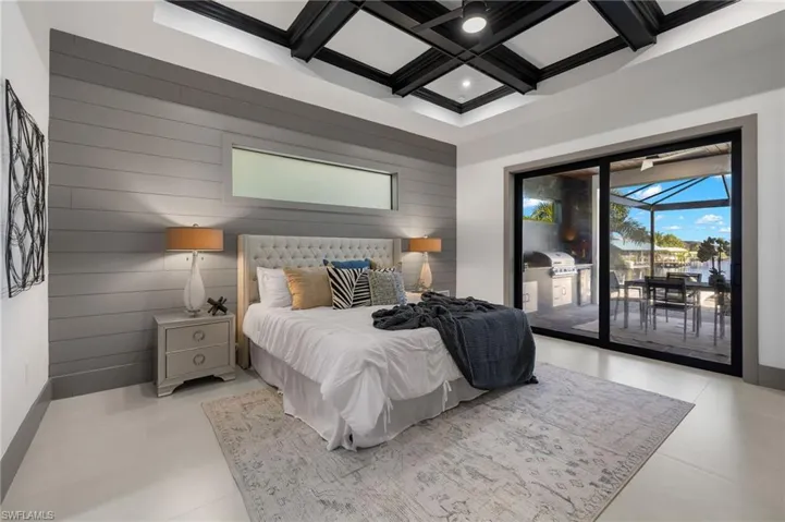 Bedroom featuring coffered ceiling, wood walls, beam ceiling, and access to outside