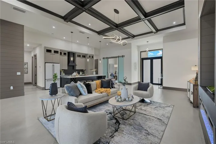 Living room with an inviting chandelier, coffered ceiling, beam ceiling, and a barn door